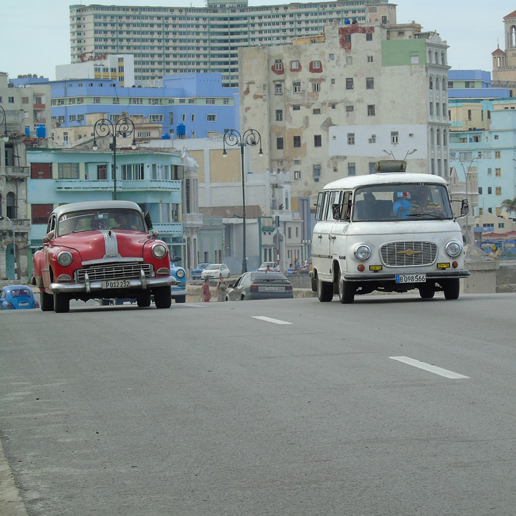 two older vehicles driving down a street